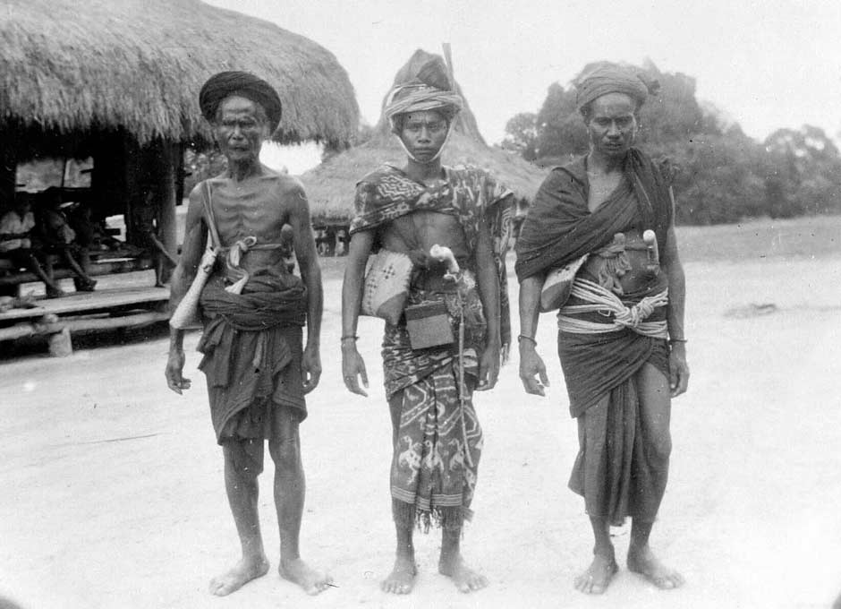 Description: A maramba noble (centre) flanked on his right by a slave dressed in two hinggi, Prainglioe, East Sumba, around 1931. L. C. Heyting Collection, Leiden University Library.jpg