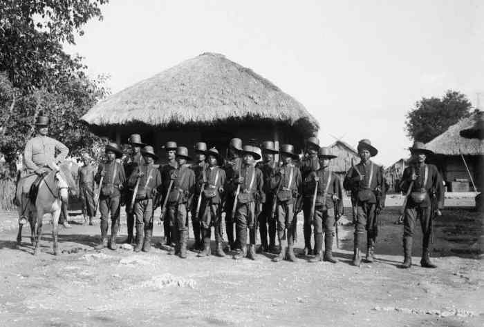 Description: Posthouder Abbink and his military police at Mamboro in 1910