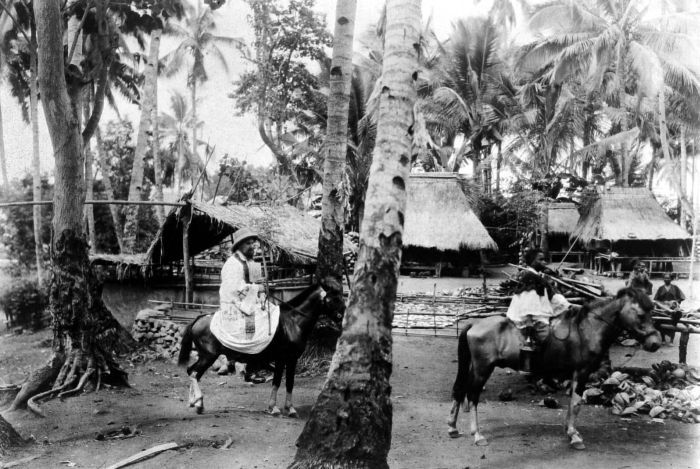 Description: A Catholic pastor entering a Flores kampong on horseback