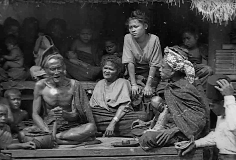 Description: The luka sémba shoulder cloth worn by the man seated to the right