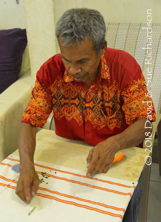 Description: Dioyonesius Haling demonstrates how he couches shells onto a textile